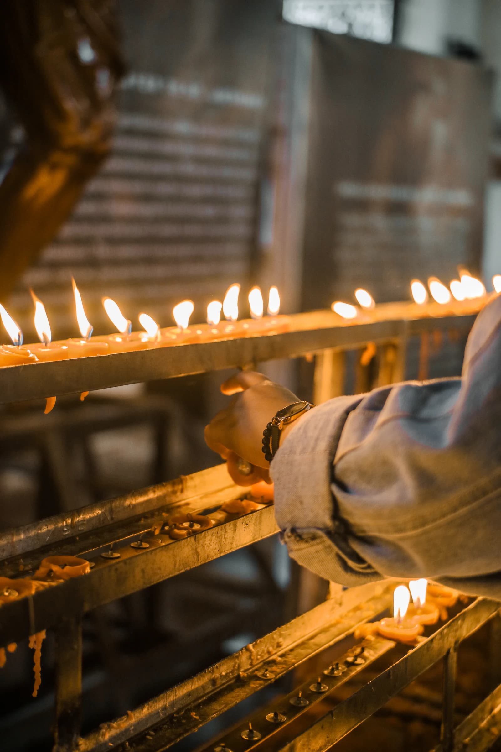 Votive candles burning on a rack.